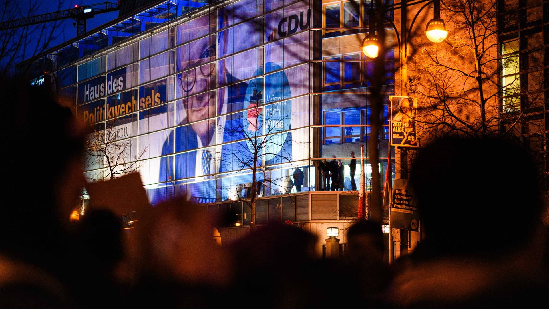 Protestteilnehmer halten in der Dämmerung vor dem Konrad-Adenauer-Haus in Berlin, der Zentrale der CDU-Bundespartei, Plakate und Schilder hoch. 