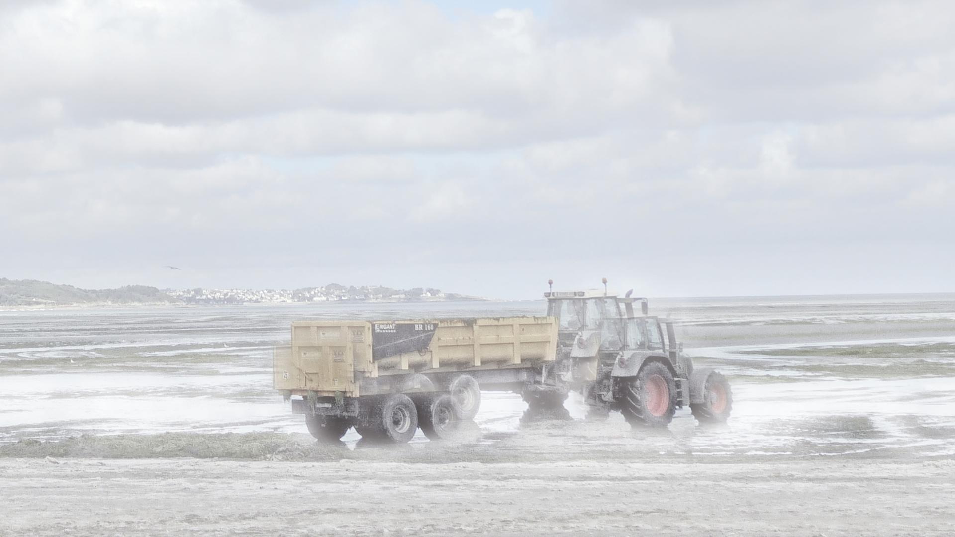 Ein Traktor am Meer, der verschwommen und teils doppelt zu sehen ist.