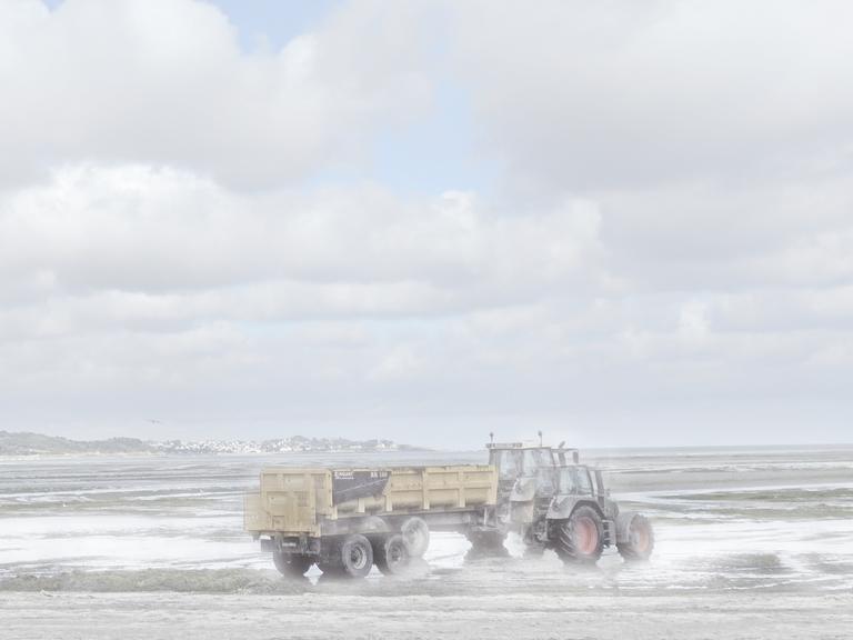 Ein Traktor am Meer, der verschwommen und teils doppelt zu sehen ist.