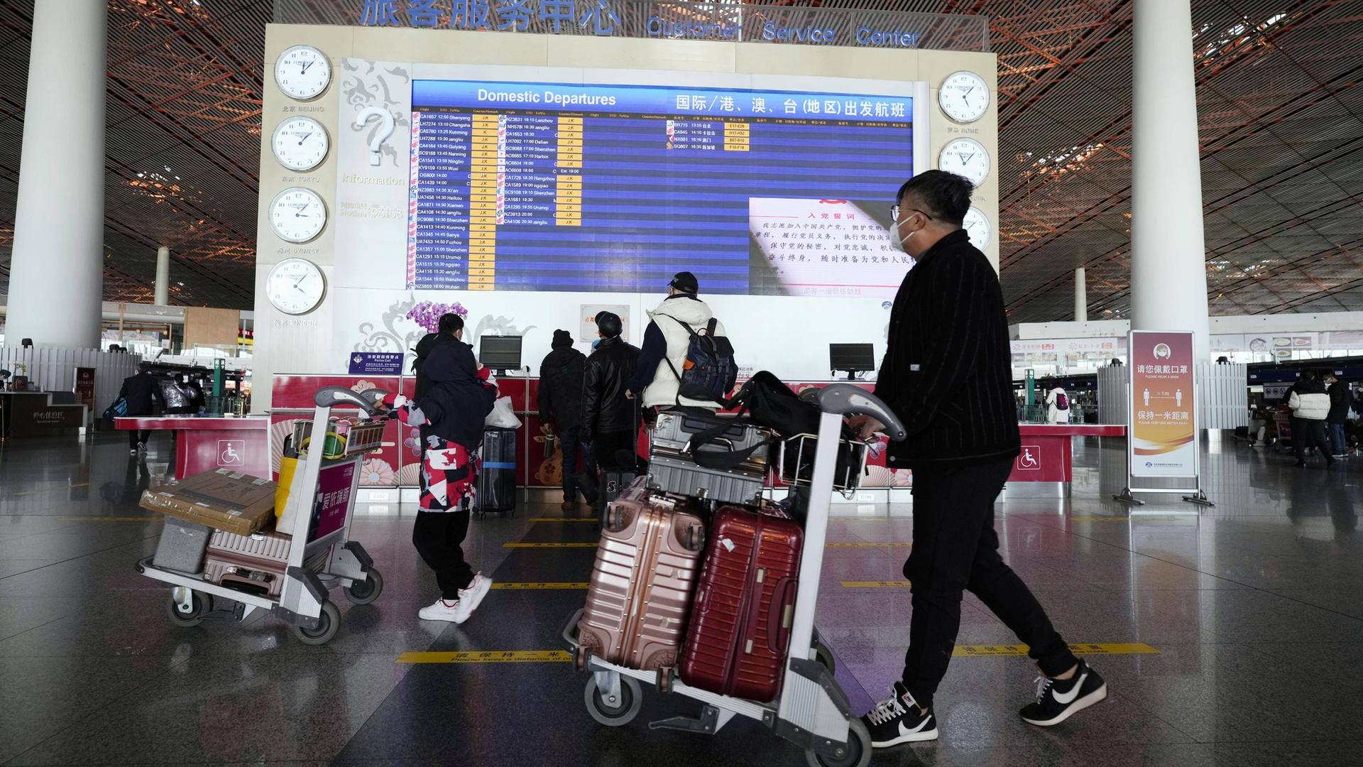 Menschen mit Gepäck an einem Flughafen in Peking