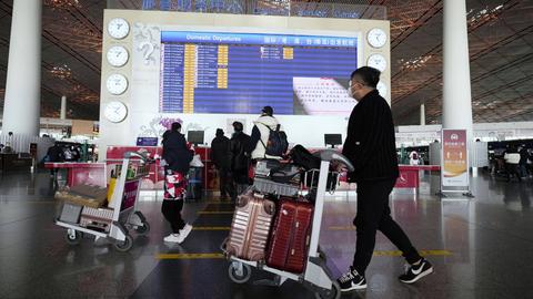 Menschen mit Gepäck an einem Flughafen in Peking.