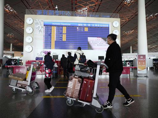 Menschen mit Gepäck an einem Flughafen in Peking.