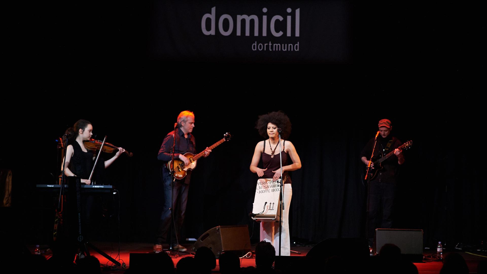 Die aus Kuba stammende Sängerin Addys Mercedes steht bei einem Konzert im Jazzclub Domicil in Dortmund mit ihren Musikern auf der Bühne, während im Hintergrund der Clubname zu lesen ist.