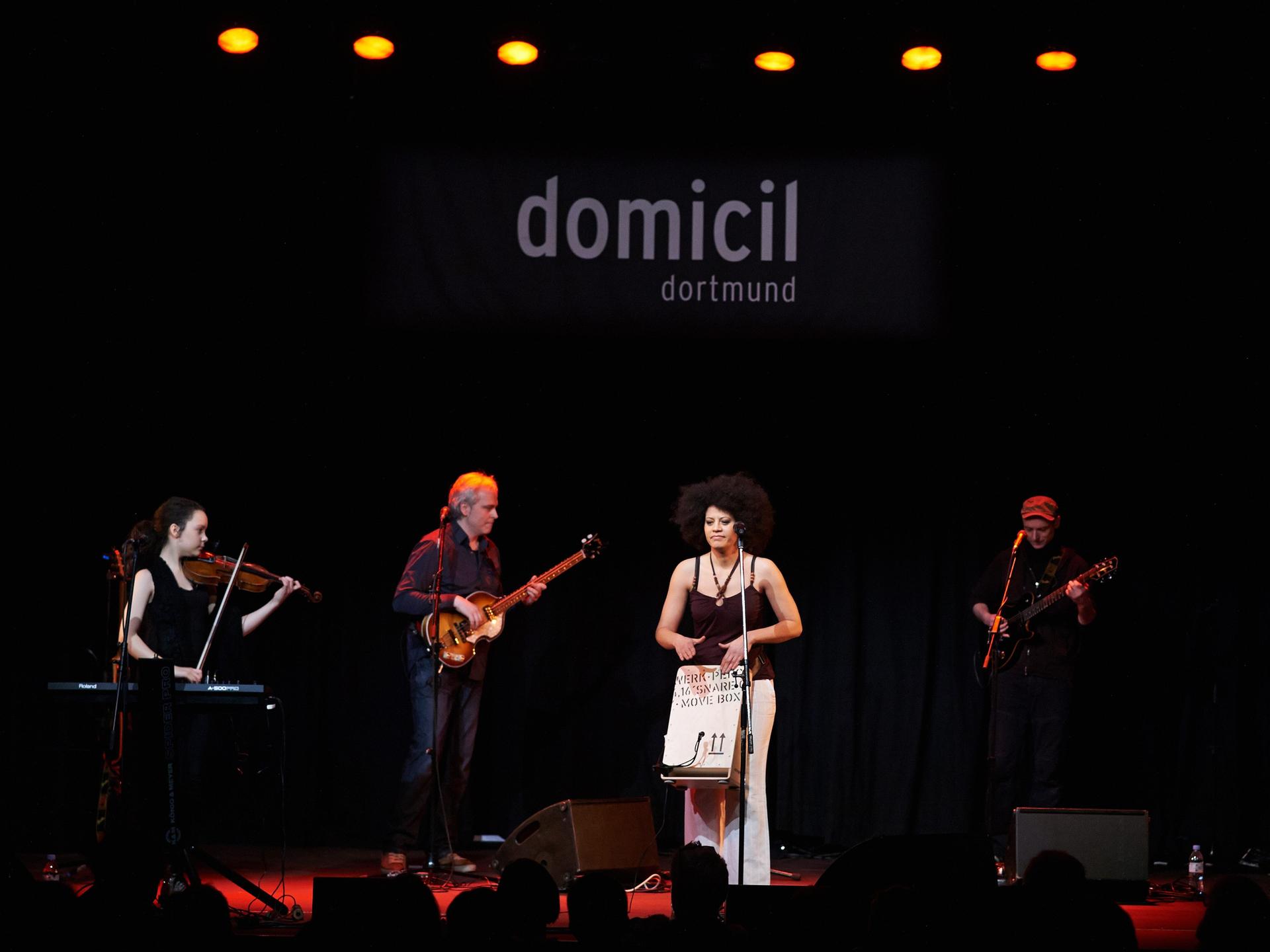 Die aus Kuba stammende Sängerin Addys Mercedes steht bei einem Konzert im Jazzclub Domicil in Dortmund mit ihren Musikern auf der Bühne, während im Hintergrund der Clubname zu lesen ist.