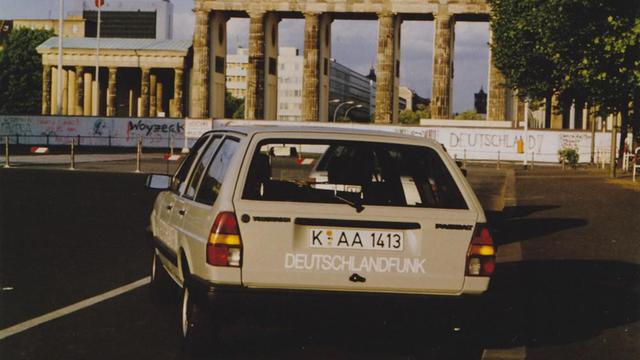 Ein Dienstwagen des Deutschlandfunk fährt 1980 vor dem Brandenburger Tor im geteilten Berlin