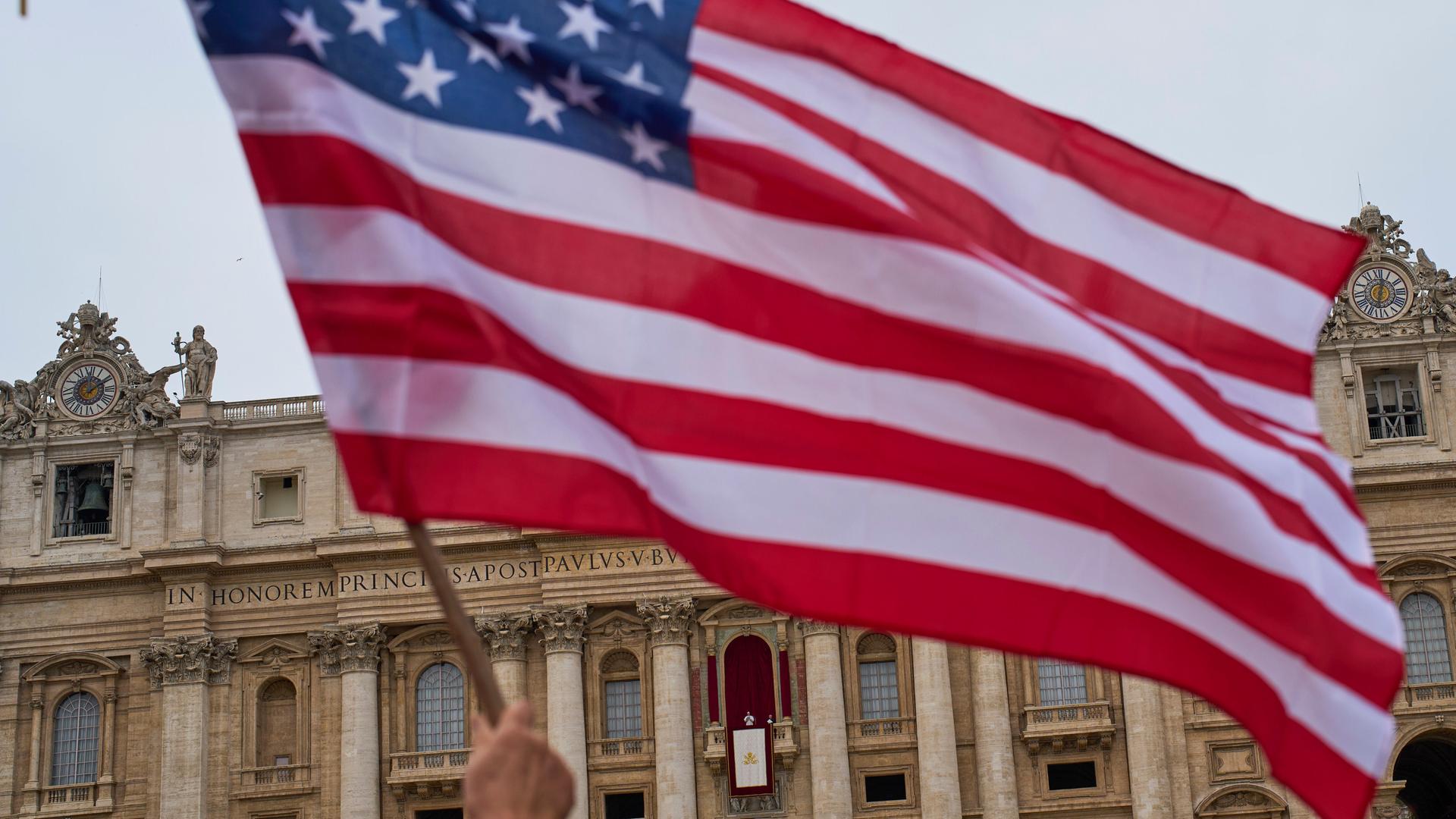 Eine USA-Flagge ist vor dem Balkon des Petersdoms zu sehen, auf dem Papst Leo XIV. steht