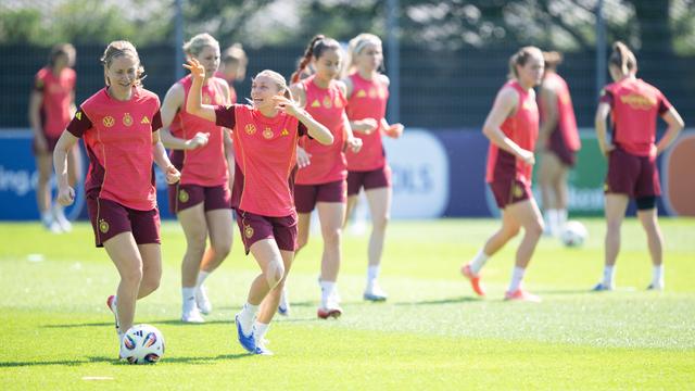 Die deutschen Fußball-Frauen laufen über den Rasen. Sie haben beim Training gute Laune.