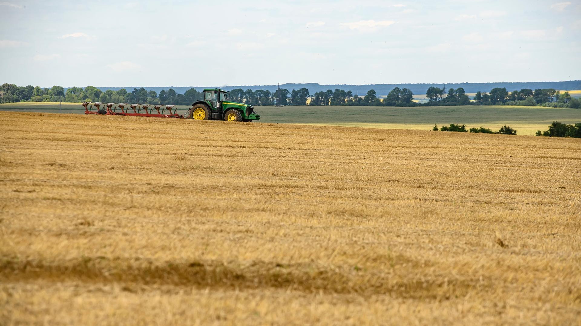 Ein Traktor fährt über Felder mit verschiedenem Getreide in der Ukraine.