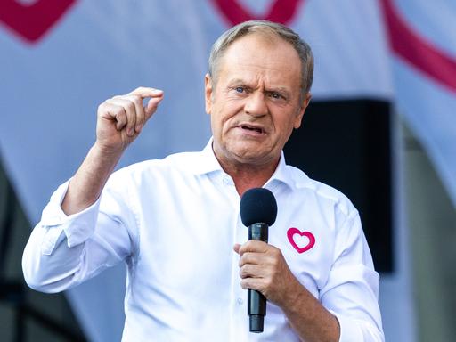 Der polnische Ministerpräsident Tusk mit Mikrofon und weißem Hemd.