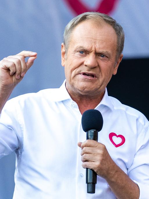 Der polnische Ministerpräsident Tusk mit Mikrofon und weißem Hemd.