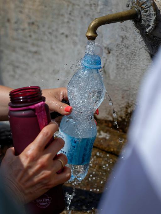 Extreme Hitze beeinträchtigt das tägliche Leben in Italien: Touristen füllen ihre Wasserflaschen an einem öffentlichen Brunnen in Rom im Sommer 2024 auf.