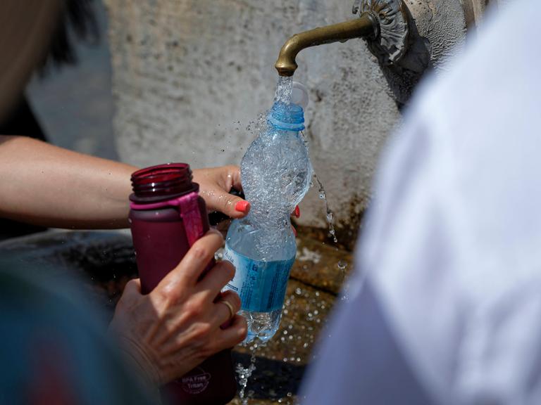 Extreme Hitze beeinträchtigt das tägliche Leben in Italien: Touristen füllen ihre Wasserflaschen an einem öffentlichen Brunnen in Rom im Sommer 2024 auf.