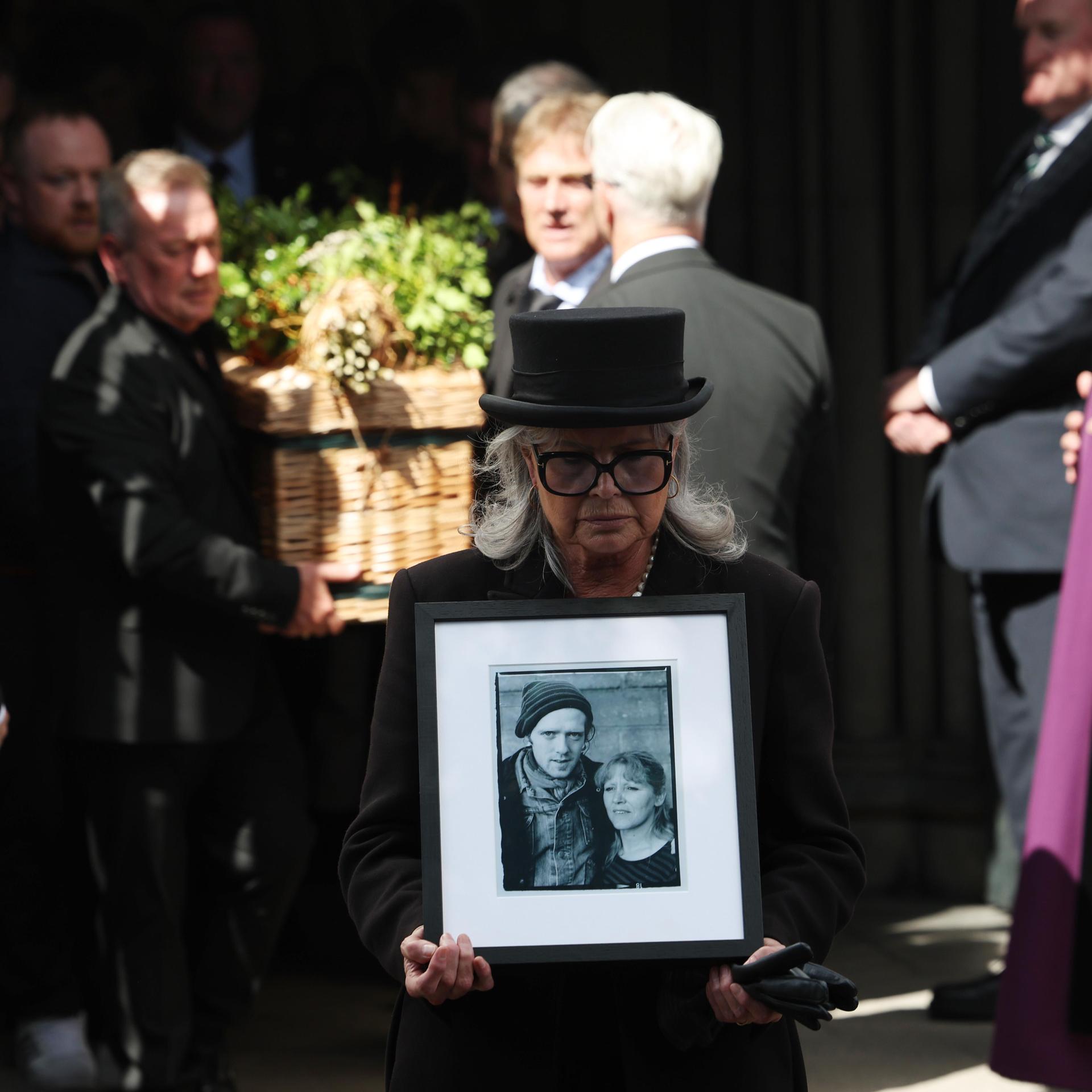 Ein Bild von Glen Hansard wird von einer Frau vor dem Sarg getragen, als dieser nach seiner Beerdigung die St. Patrick’s Cathedral in Dublin verlässt. Der Oscar-prämierte irische Musiker und Aktivist starb letzte Woche bei einem Motorradunfall.
