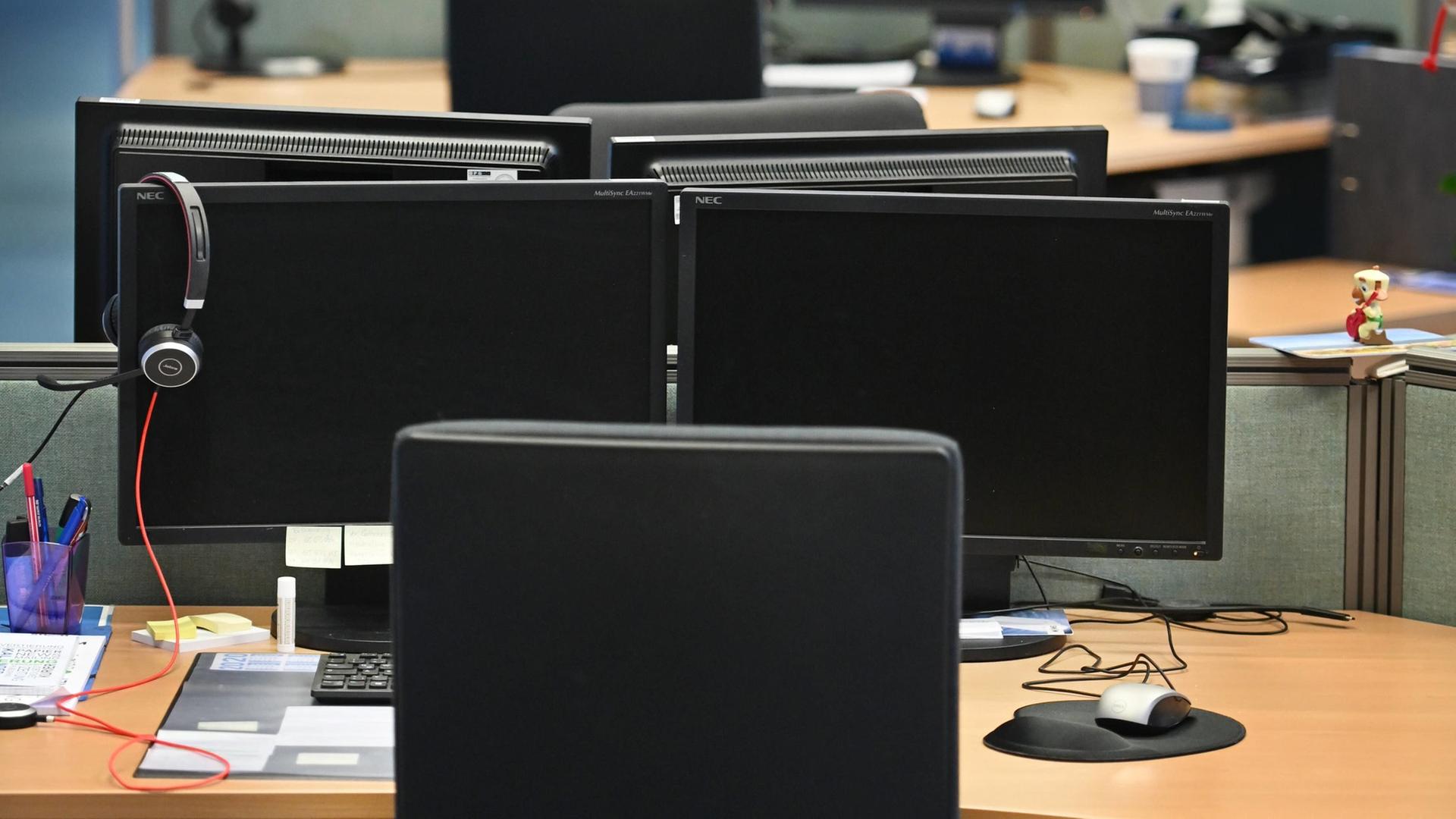 Ein leeres Großraumbüro mit ausgeschalteten Computern.