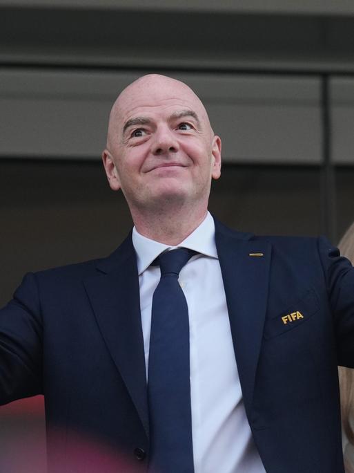 FIFA-Präsident Gianni Infantino hat die Arme ausgebreitet und hält dabei die Hände nach oben. Er trägt einen dunkelblauen Anzug. FIFA-Präsident Gianni Infantino hat die Arme ausgebreitet und hält dabei die Hände nach oben. Er trägt einen dunkelblauen Anzug.