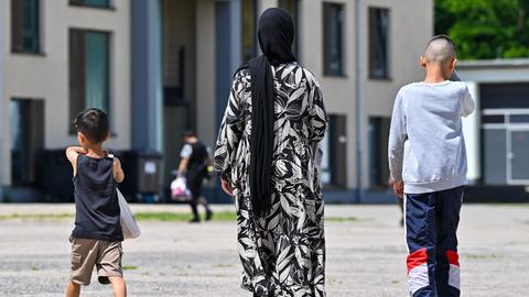 Eine Migrantin und ihre zwei Kinder gehen über das Gelände der Zentralen Erstaufnahmeeinrichtung für Asylbewerber des Landes Brandenburg in Eisenhüttenstadt.
