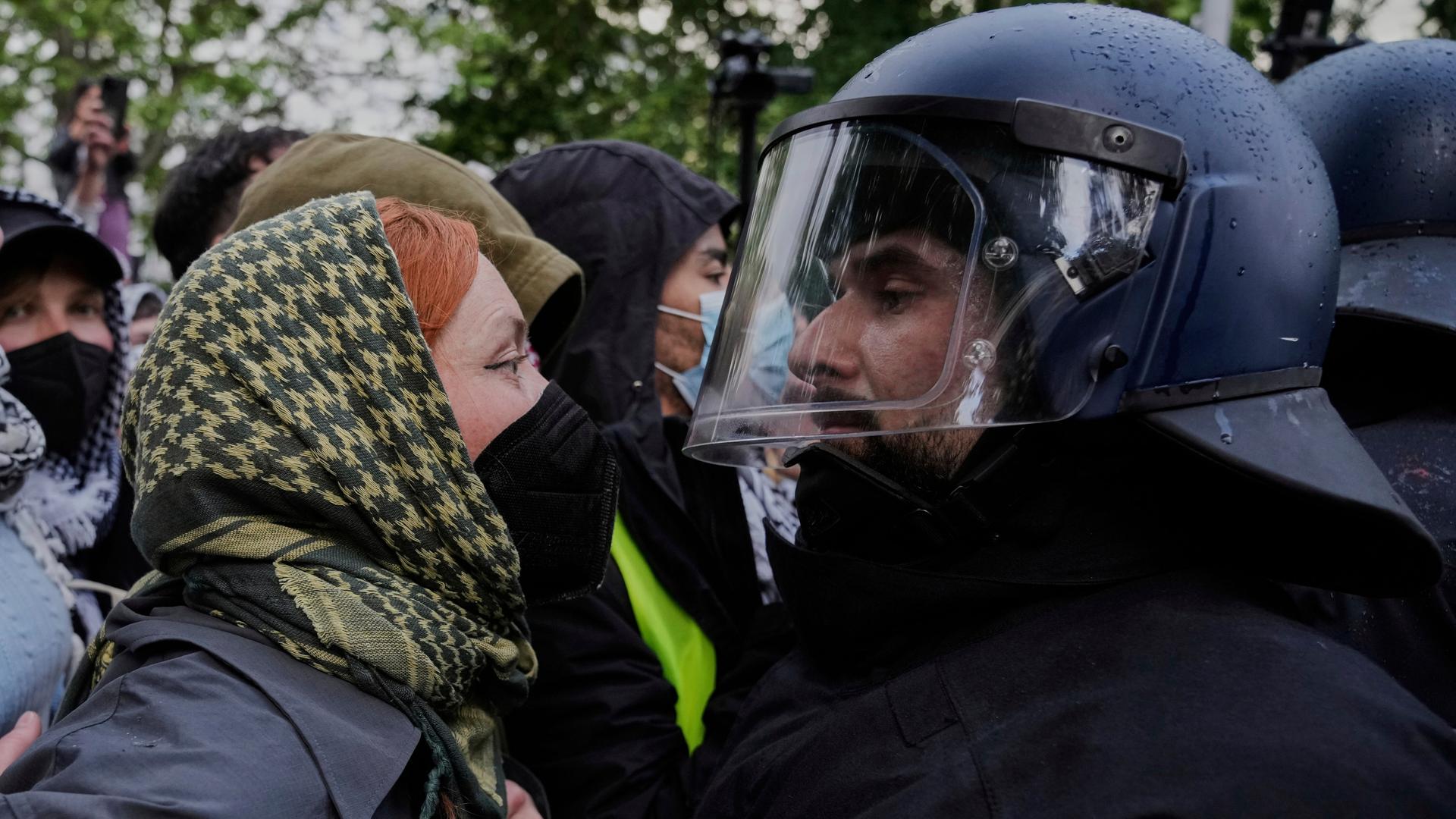Eine Demonstrantin und ein Polizist stehen sich Gesicht an Gesicht gegen-über. Eine Demonstrantin und ein Polizist stehen sich Gesicht an Gesicht gegen-über.