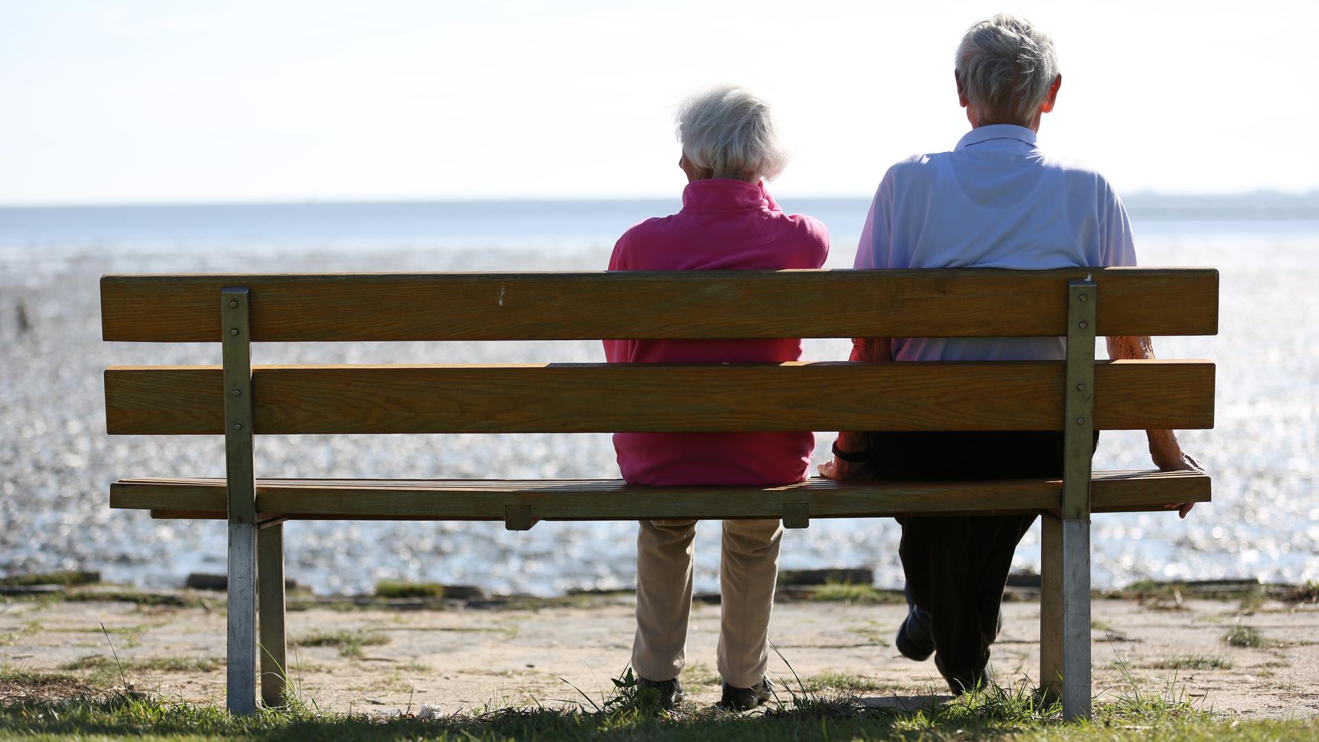 Ein Senioren-Paar sitzt auf einer Bank und schaut auf das im Watt vor Dagebüll in Schleswig-Holstein.