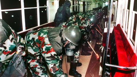 Soldaten in Schutzanzügen reinigen einen U-Bahnwagen.