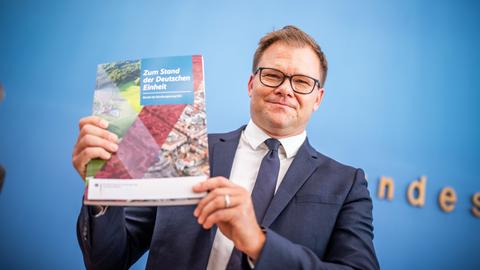 Berlin: Carsten Schneider (SPD), Staatsminister und Ostbeauftragter der Bundesregierung, zeigt den Bericht zum Stand der Deutschen Einheit.