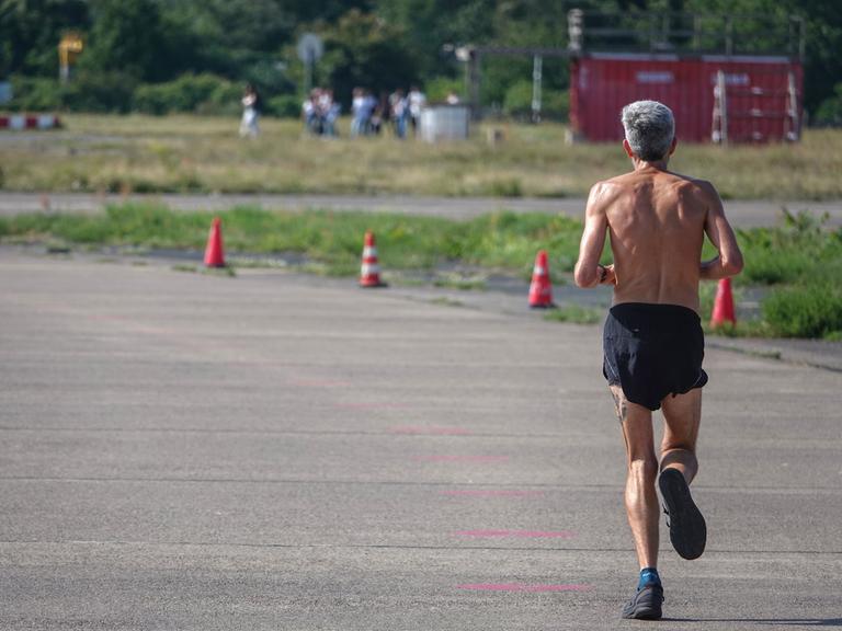 Ein Mann joggt auf einem stillgelegten Rollfeld auf dem Tempelhofer Feld in Berlin.