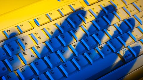 Schatten einer Hand über einer Computertastatur Schatten einer Hand über einer Computertastatur