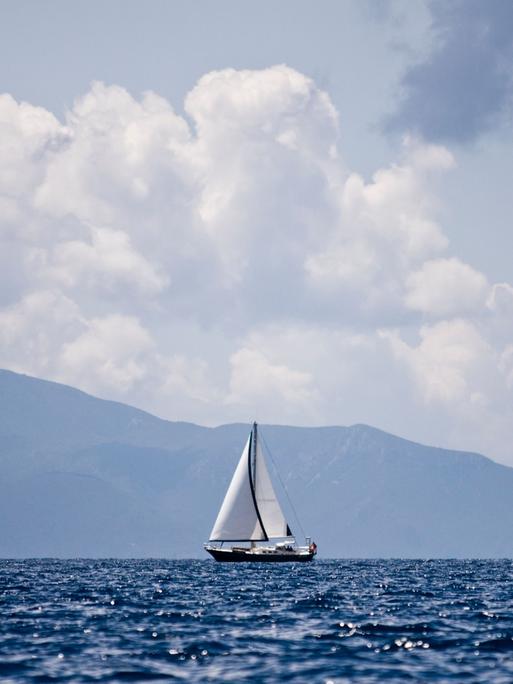 Segelboot auf See vor Bergen und Himmel.