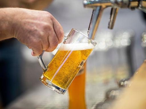 Ein Bier wird in einer Berliner Kneipe an einem Hahn in einen Glaskrug gezapft.