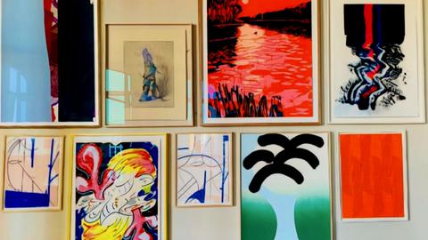 Neun gerahmte Bilder hängen an einer Wand. Das Foto wurde auf der Releaseparty der Handsiebdruckerei Editionen gemacht.