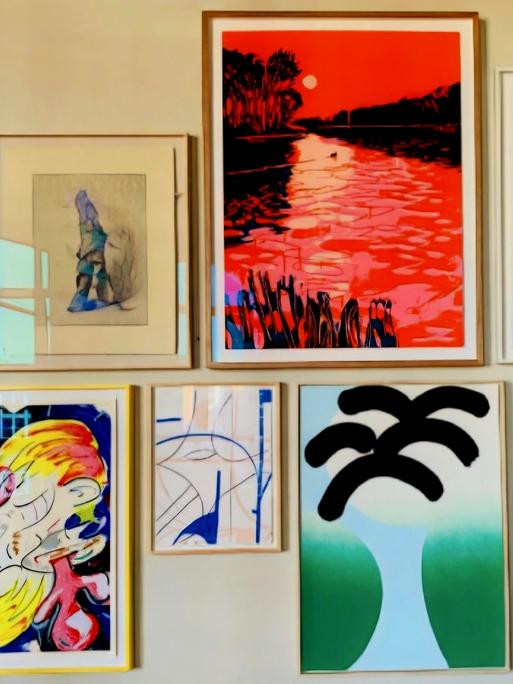 Neun gerahmte Bilder hängen an einer Wand. Das Foto wurde auf der Releaseparty der Handsiebdruckerei Editionen gemacht. Neun gerahmte Bilder hängen an einer Wand. Das Foto wurde auf der Releaseparty der Handsiebdruckerei Editionen gemacht.