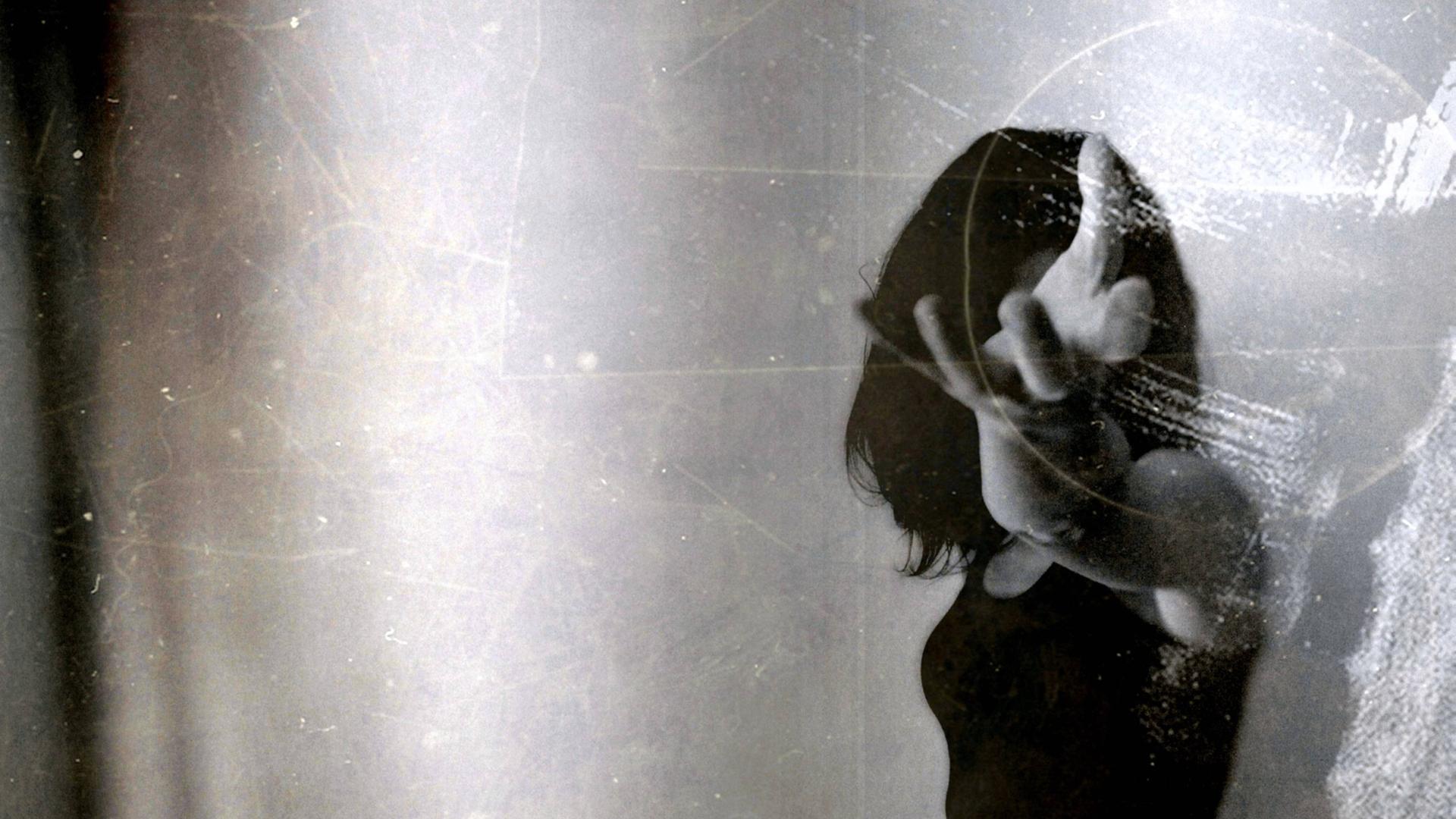 Schwarz-Weiß-Bild einer jungen Frau, die ihren Arm und ihre Hand in Richtung Kamera streckt, als würde sie etwas halten, und damit ihr Gesicht verdeckt. Schwarz-Weiß-Bild einer jungen Frau, die ihren Arm und ihre Hand in Richtung Kamera streckt, als würde sie etwas halten, und damit ihr Gesicht verdeckt.