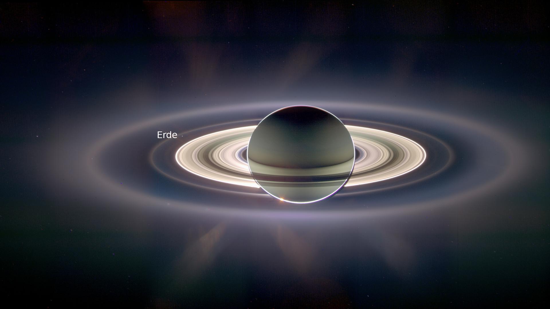 Saturn im Gegenlicht, aufgenommen von der Raumsonde Cassini. Der kleine Punkt am Rand des Ringsystems ist die Erde.