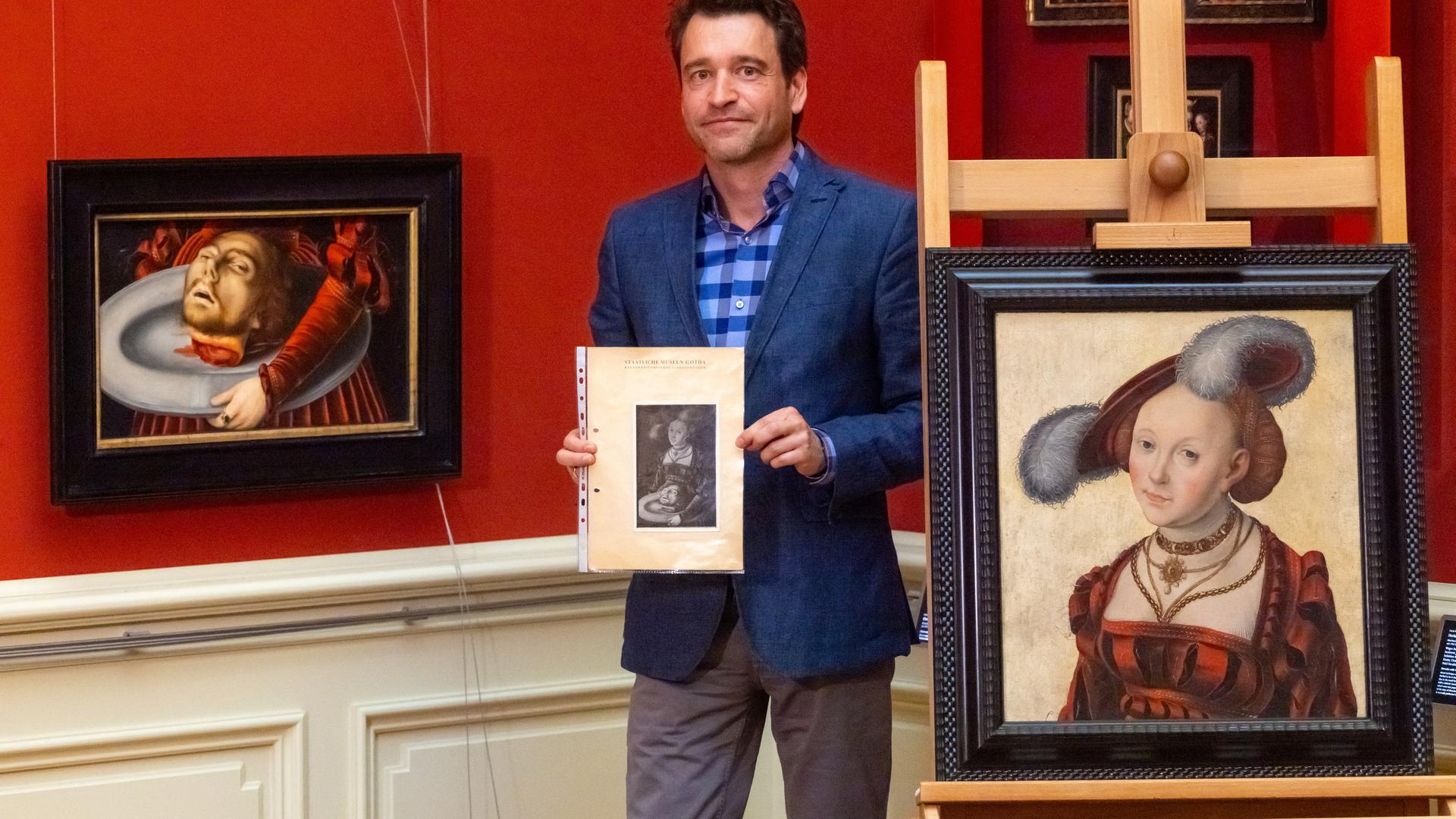 Timo Trümper, Direktor Wissenschaft und Sammlungen der Friedenstein Stiftung Gotha, steht mit einem historischen Foto des ursprünglichen Gemäldes zwischen den beiden Fragmenten des Gemäldes "Die zersägte Salome". Timo Trümper, Direktor Wissenschaft und Sammlungen der Friedenstein Stiftung Gotha, steht mit einem historischen Foto des ursprünglichen Gemäldes zwischen den beiden Fragmenten des Gemäldes "Die zersägte Salome".