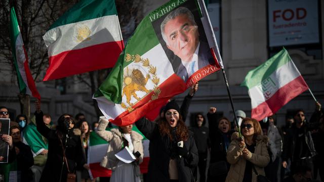 Mehrere Menschen halten grün-weiß-rote iranische Flaggen ohne das Emblem der Islamischen Republik hoch. In der Bildmitte trägt eine Person eine Fahne mit einem Porträt von Reza Pahlavi, dem Sohn des 1979 gestürzten Schahs. 