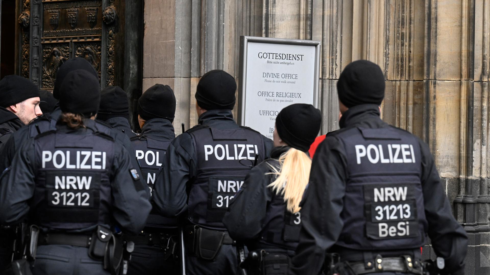 Polizisten gehen im Eingang des Kölner Doms am Weihnachtstag. Aufgrund von Hinweisen auf einen geplanten islamistischen Anschlag hat die Polizei die SicherheitsmaÃnahmen hochgefahren.