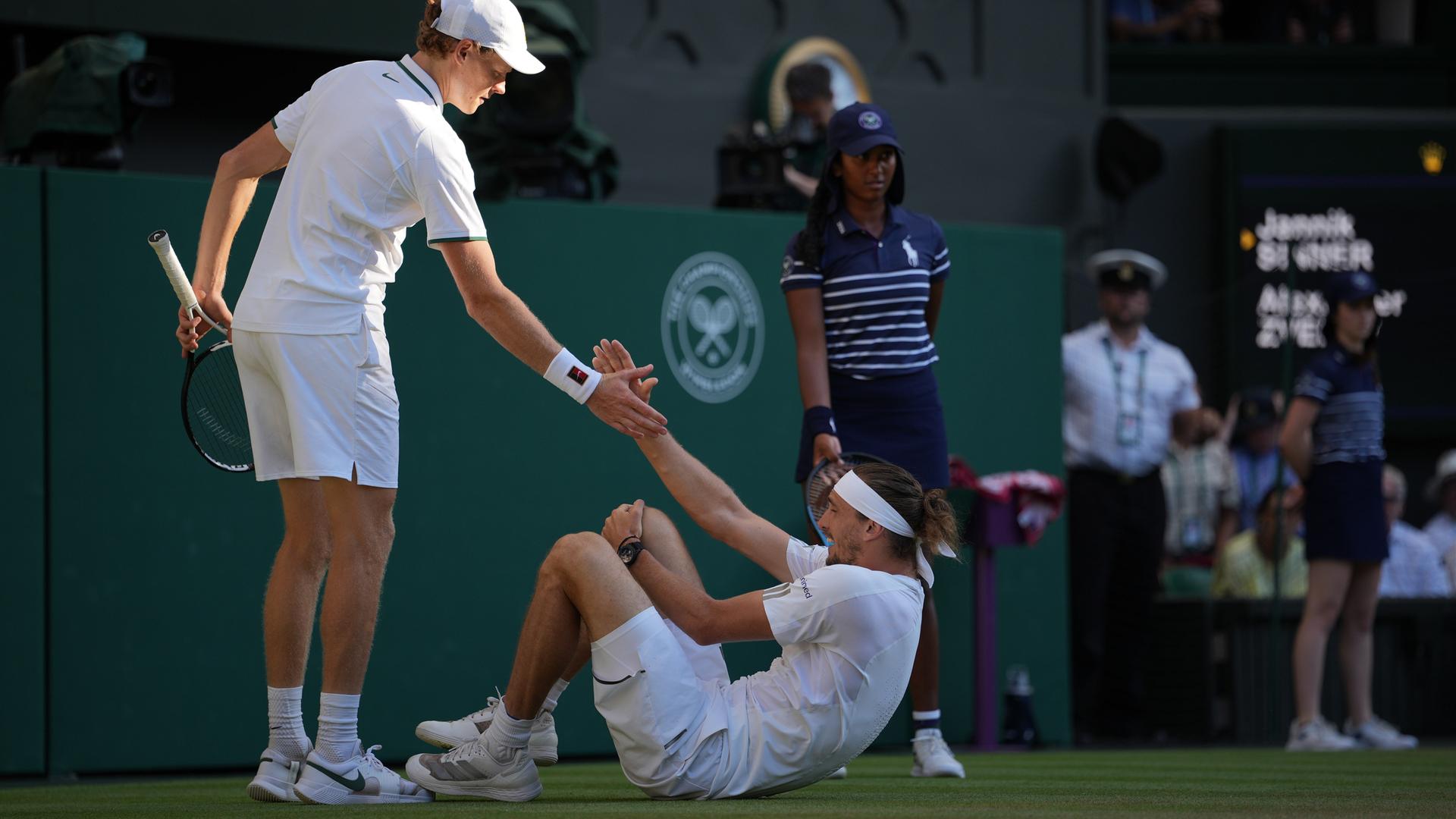 Tennis-Spieler Jannik Sinner hilft Alexander Zverev auf, der während des Wimbledon-Finales gestürzt war. Tennis-Spieler Jannik Sinner hilft Alexander Zverev auf, der während des Wimbledon-Finales gestürzt war.