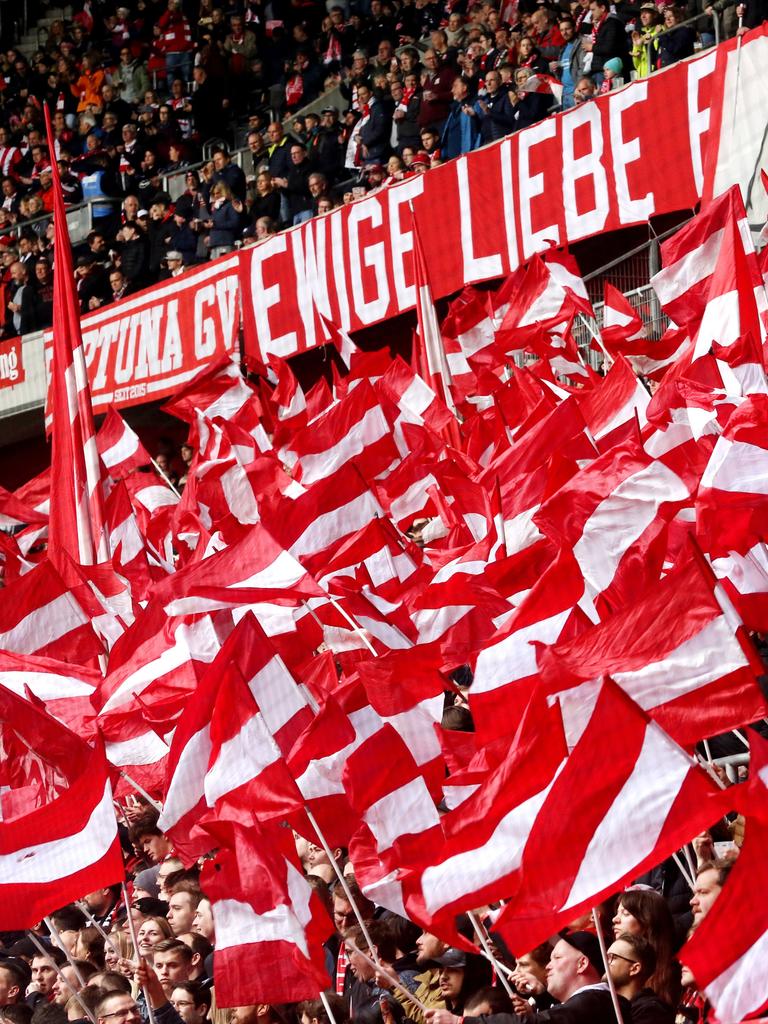 In der Fankurve von Fortuna Düsseldorf werden zahlreiche rot-weiße Fahnen geschwenkt.