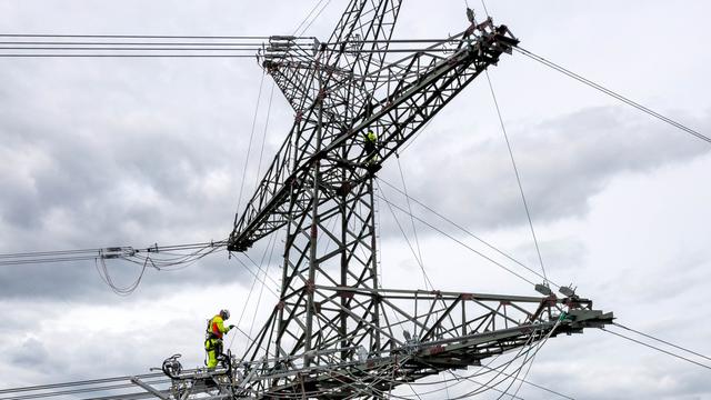 Das Foto zeigt einen Arbeiter auf einem Strommast
