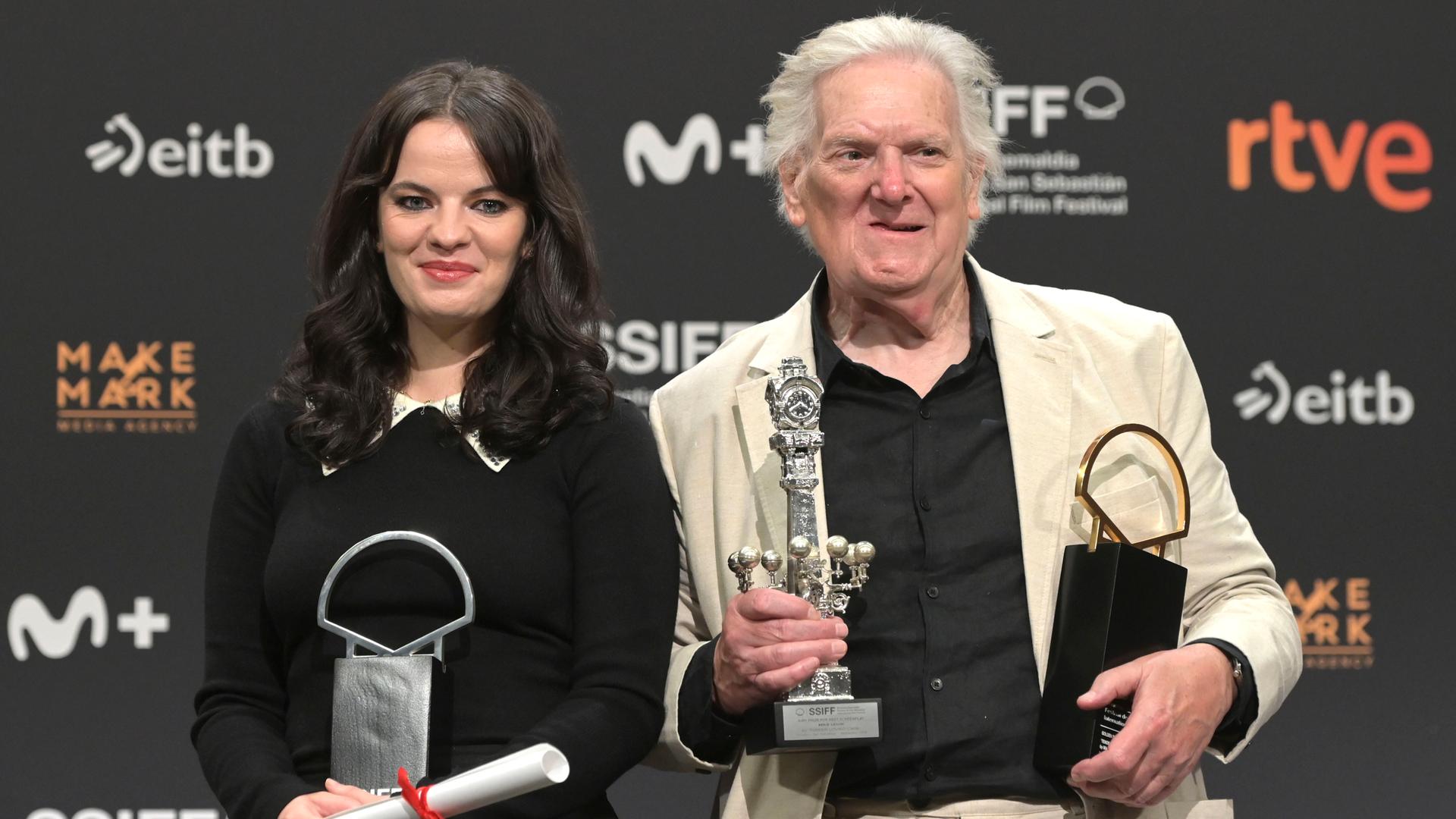 Die Schauspielerin Alice Bailey Johnson und der Schauspieler Paul Jesson halten beim Filmfefst in San Sebastian mehrere Preise in ihren Händen. Hinter ihnen eine Wand mit den Logos der Sponsoren. Die Schauspielerin Alice Bailey Johnson und der Schauspieler Paul Jesson halten beim Filmfefst in San Sebastian mehrere Preise in ihren Händen. Hinter ihnen eine Wand mit den Logos der Sponsoren.