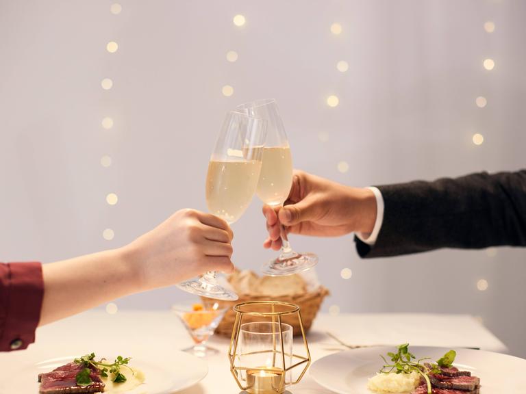 Mann und Frau stoßen mit Champagner an.