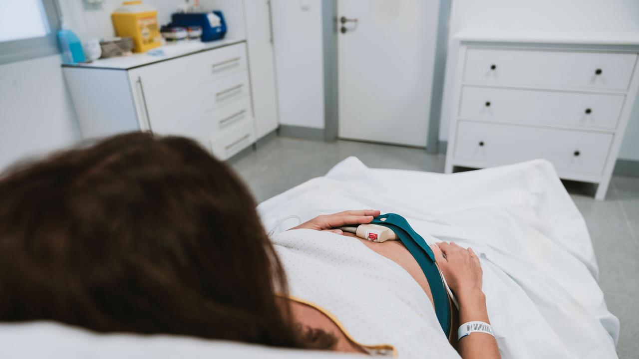 Eine schwangere Frau liegt in einem Krankenhausbett.