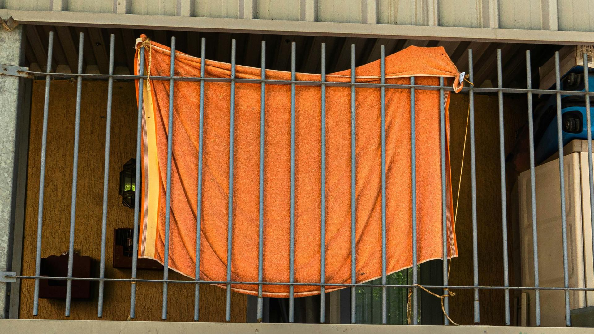 Ein orangefarbenes Stoffstück ist an Gitterstäbe geknüpft Ein orangefarbenes Stoffstück ist an Gitterstäbe geknüpft