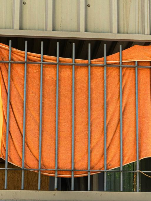Ein orangefarbenes Stoffstück ist an Gitterstäbe geknüpft