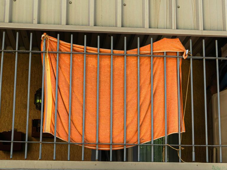 Ein orangefarbenes Stoffstück ist an Gitterstäbe geknüpft