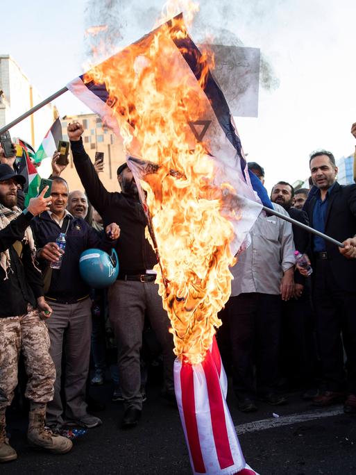 Protestierende in Teheran verbrennen israelische und US-amerikanische Nationalflaggen. 