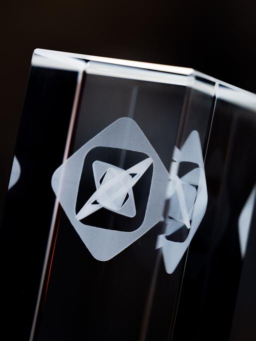 Ein Bildausschnitt der gläsernen Trophäe zeigt das Grimme-Logo.