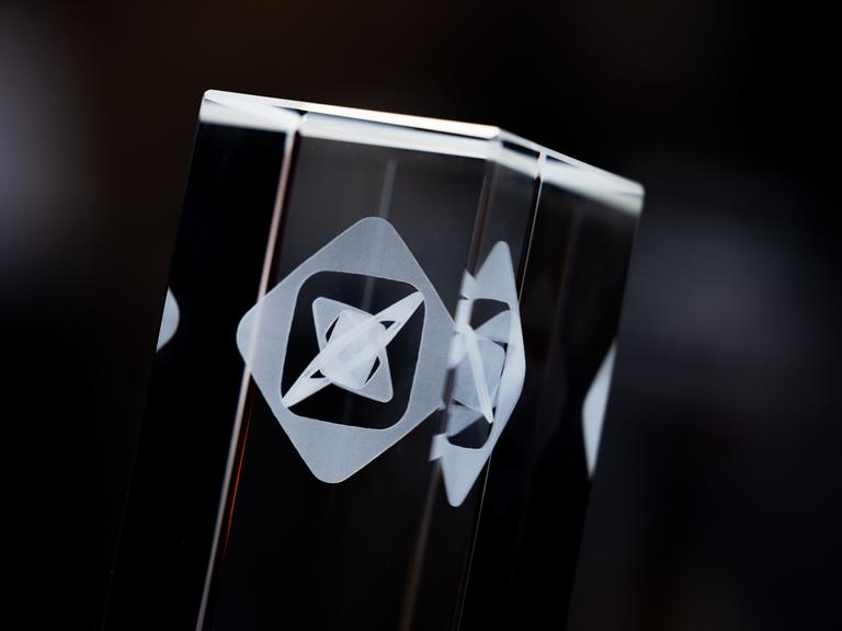 Ein Bildausschnitt der gläsernen Trophäe zeigt das Grimme-Logo.