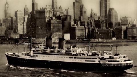 Historisches Schwarzweißfoto: Das Dampfschiff MS Berlin kreuzt vor der Silhouette New Yorks.