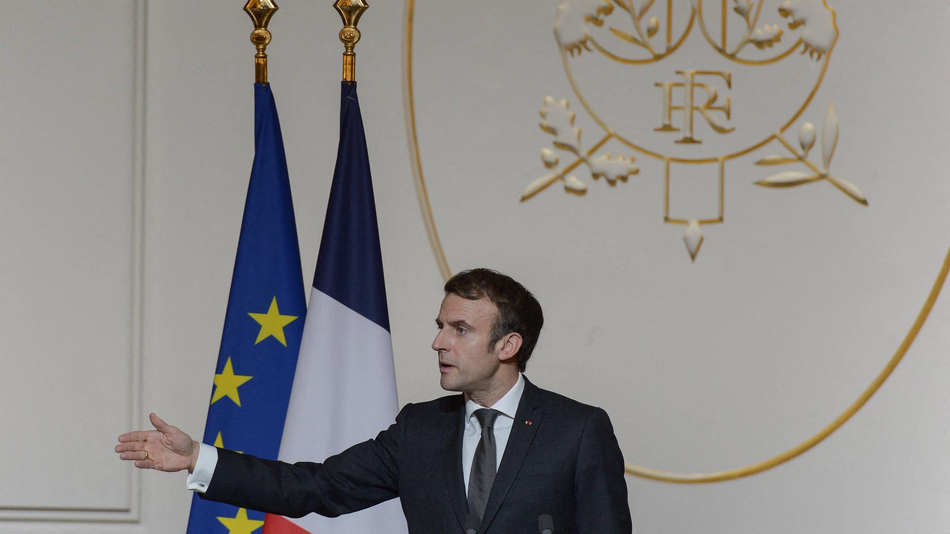 Der französische Präsident Macron hält eine Rede und zeigt mit seinem Arm nach links.