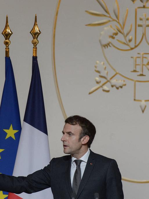 Der französische Präsident Macron hält eine Rede und zeigt mit seinem Arm nach links.